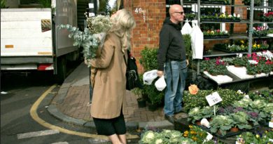 A woman struggling to carry flowers on Columbia Road