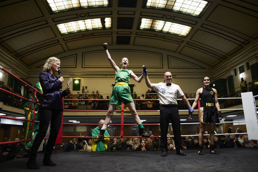 Repton Boxing Club female competitor winner announced, as she jumps in the air celebrating in York Hall, Bethnal Green.