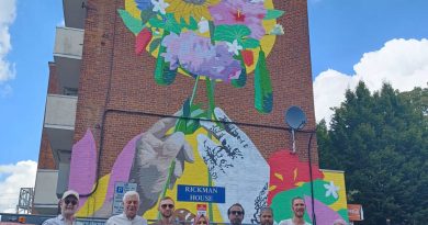 Residents gather under their new mural featuring colourful flowers from their resident countries, on Bancroft estate in Bethnal Green.