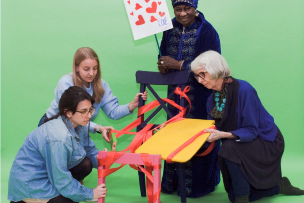 Participants in Magic Me's workshop gather around a deconstructed chair trying to hold parts of it together.