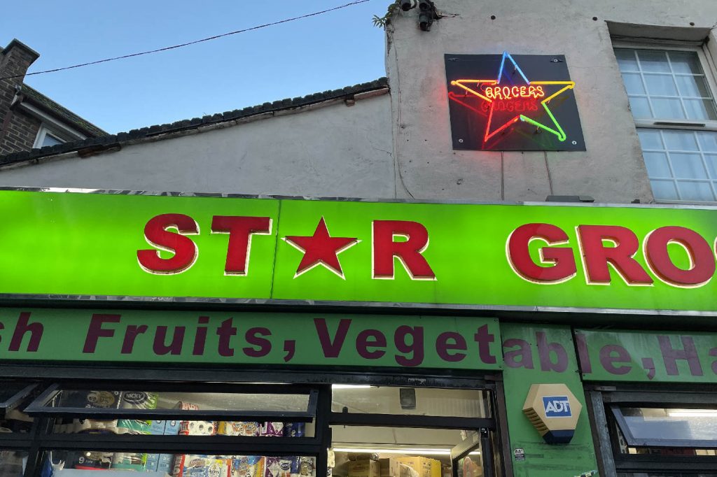 A neon star sign crowns the signage of Star Grocer's in Bethnal Green