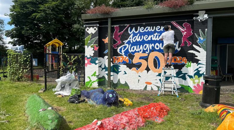 An artist adds details to the Weavers Field 50th Anniversary mural.